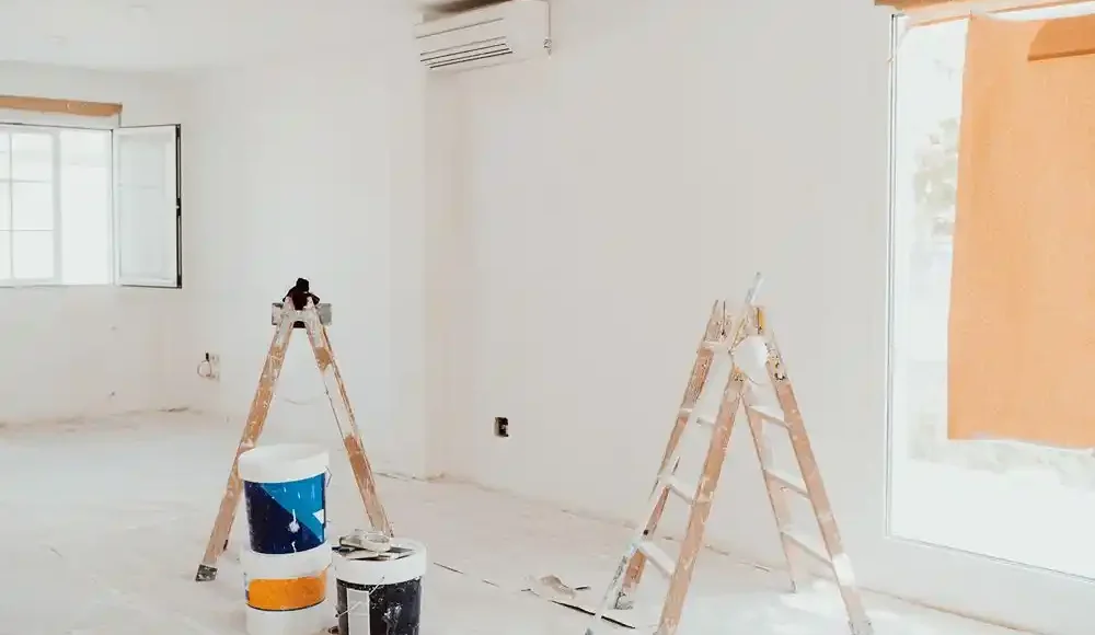 Boya kovaları ve merdivenlerin bulunduğu, boyanmakta olan aydınlık bir iç mekân