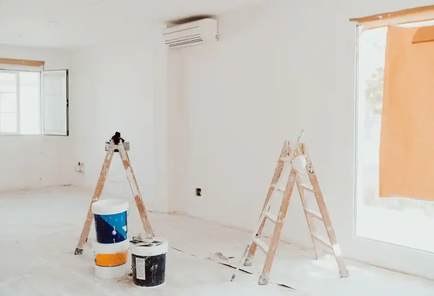 Boya kovaları ve merdivenlerin bulunduğu, boyanmakta olan aydınlık bir iç mekân