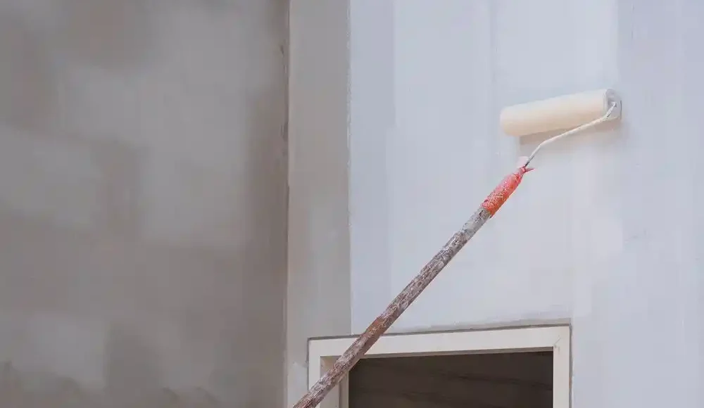 Beyaz bir duvarı boyamak için kullanılan rulo fırça